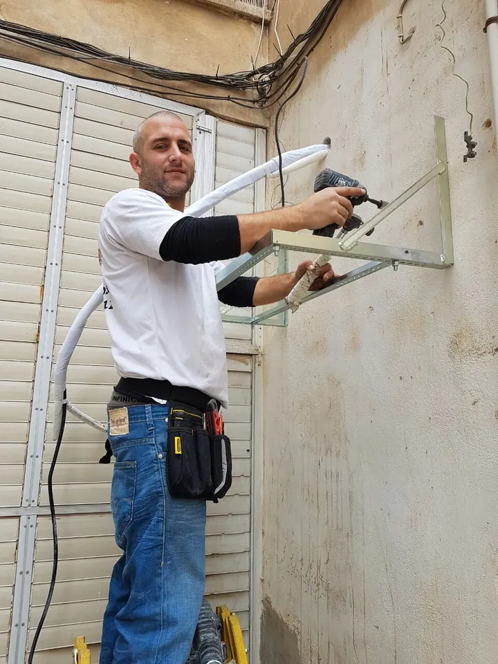 אוהד יעקובי מתקין מתקן ליחידת חוץ על קיר